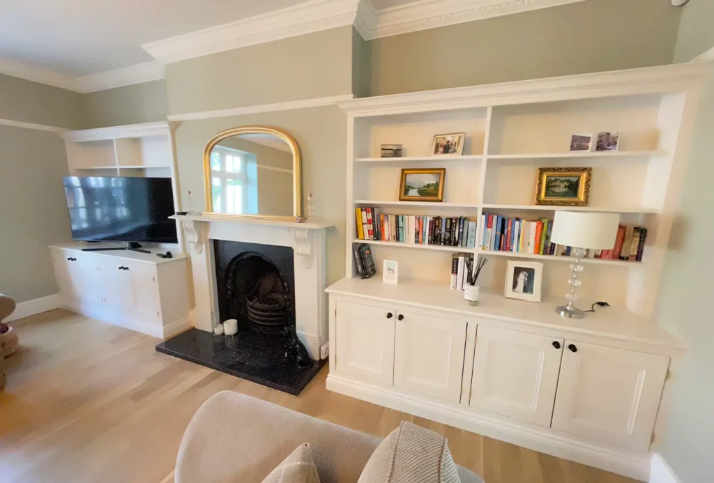 White painted alcove cupboards and bookshelves either side of a cast iron fireplace