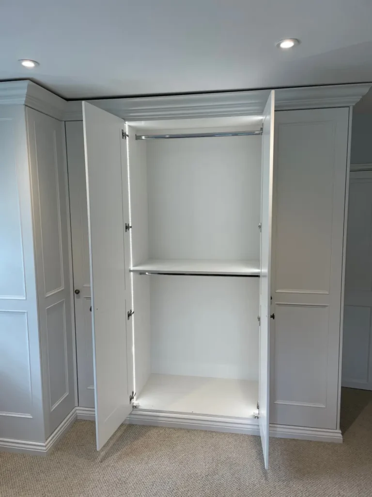 Painted fitted wardrobe with doors open showing two hanging rails and LED strip lighting